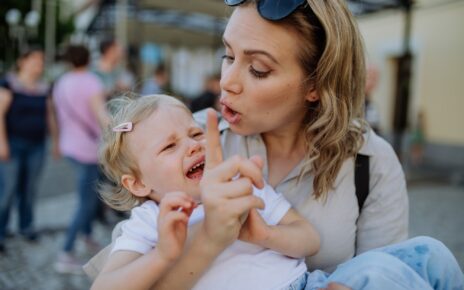 Mother scolding her little daughter in street. Child is crying and woman is shaking finger because